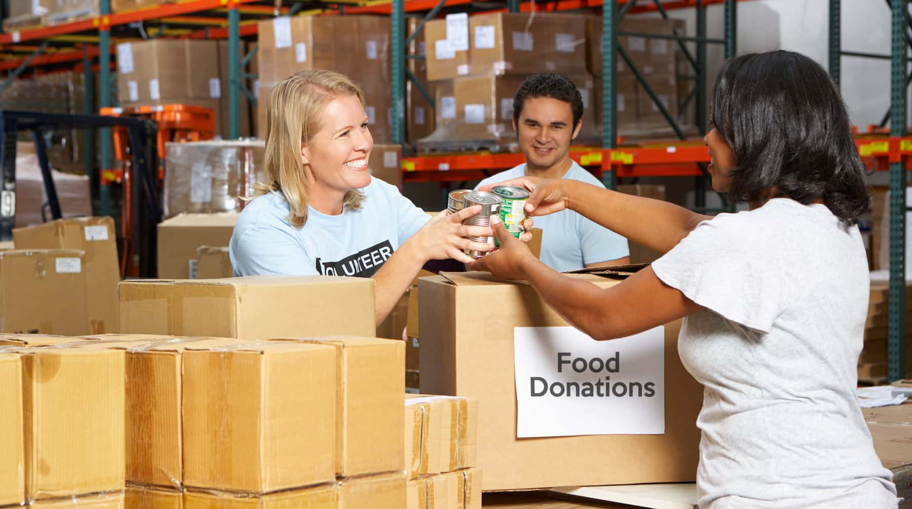 People passing canned food across donation boxes in a warehouse